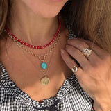 necklace stack for summer with red coral beaded strand, a gold chain with a turquoise oval pendant, and a gold chain with a round gold coin pendant.