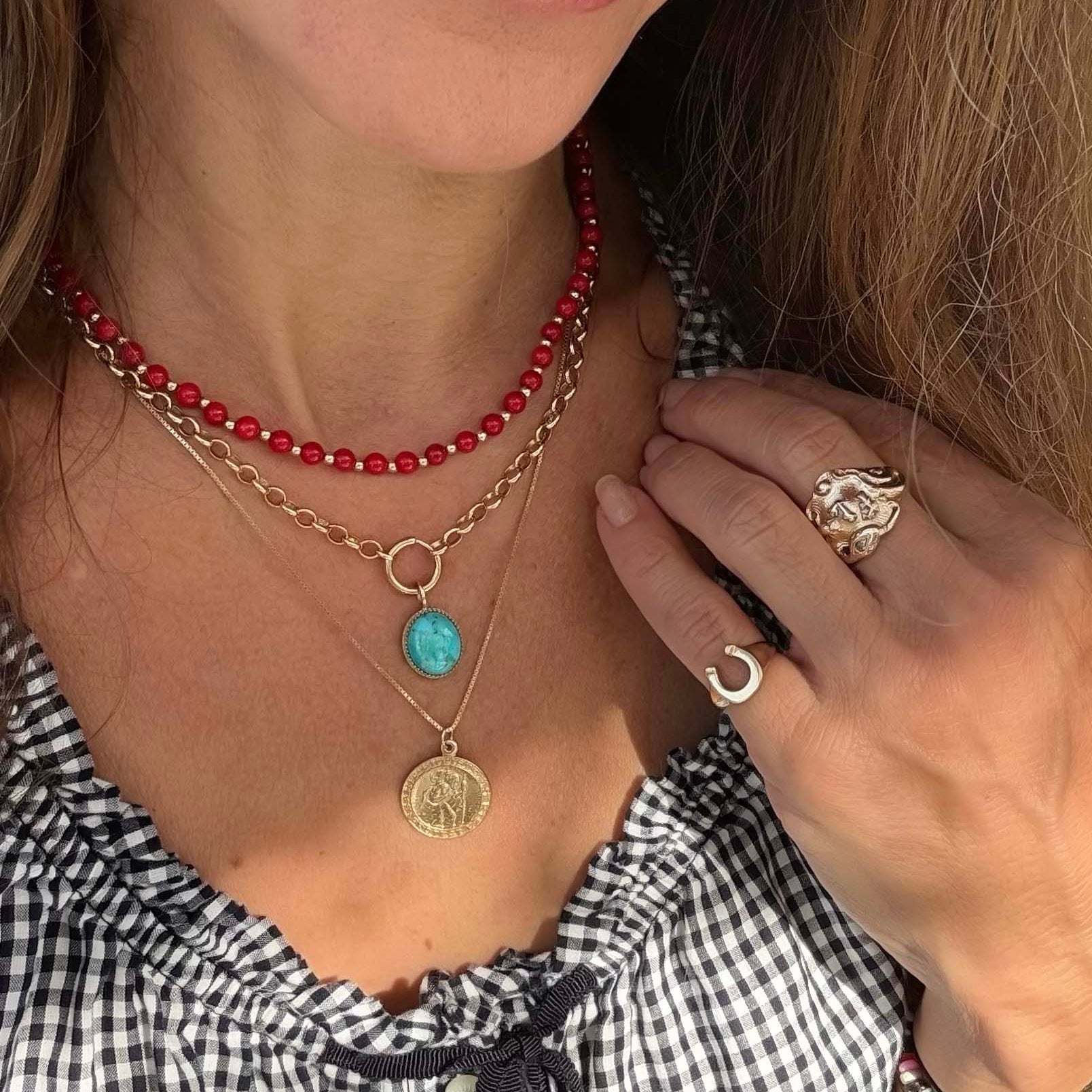 necklace stack for summer with red coral beaded strand, a gold chain with a turquoise oval pendant, and a gold chain with a round gold coin pendant.