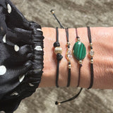 Close-up of a wrist wearing multiple macrame bracelets with beads, CZ stones,